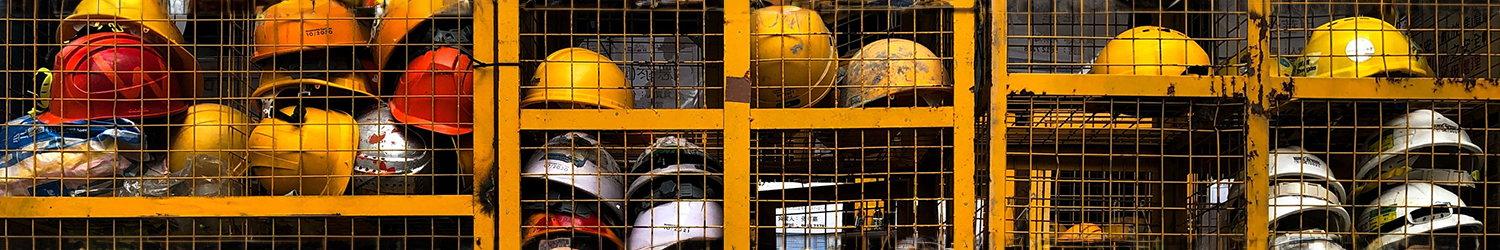 many stacks of different colored hard hats in a yellow metal cage