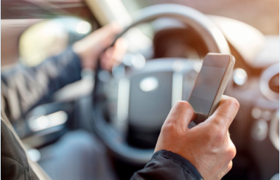 image of the man driving with one hand on the steering wheel and a cellphone in the other hand.